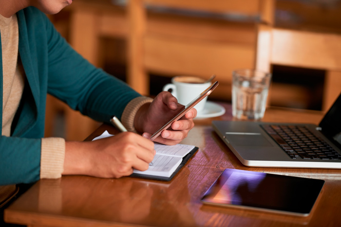 Registro de anotações em papel com apoio de celular, representando o processo de formalização empresarial com endereço fiscal.