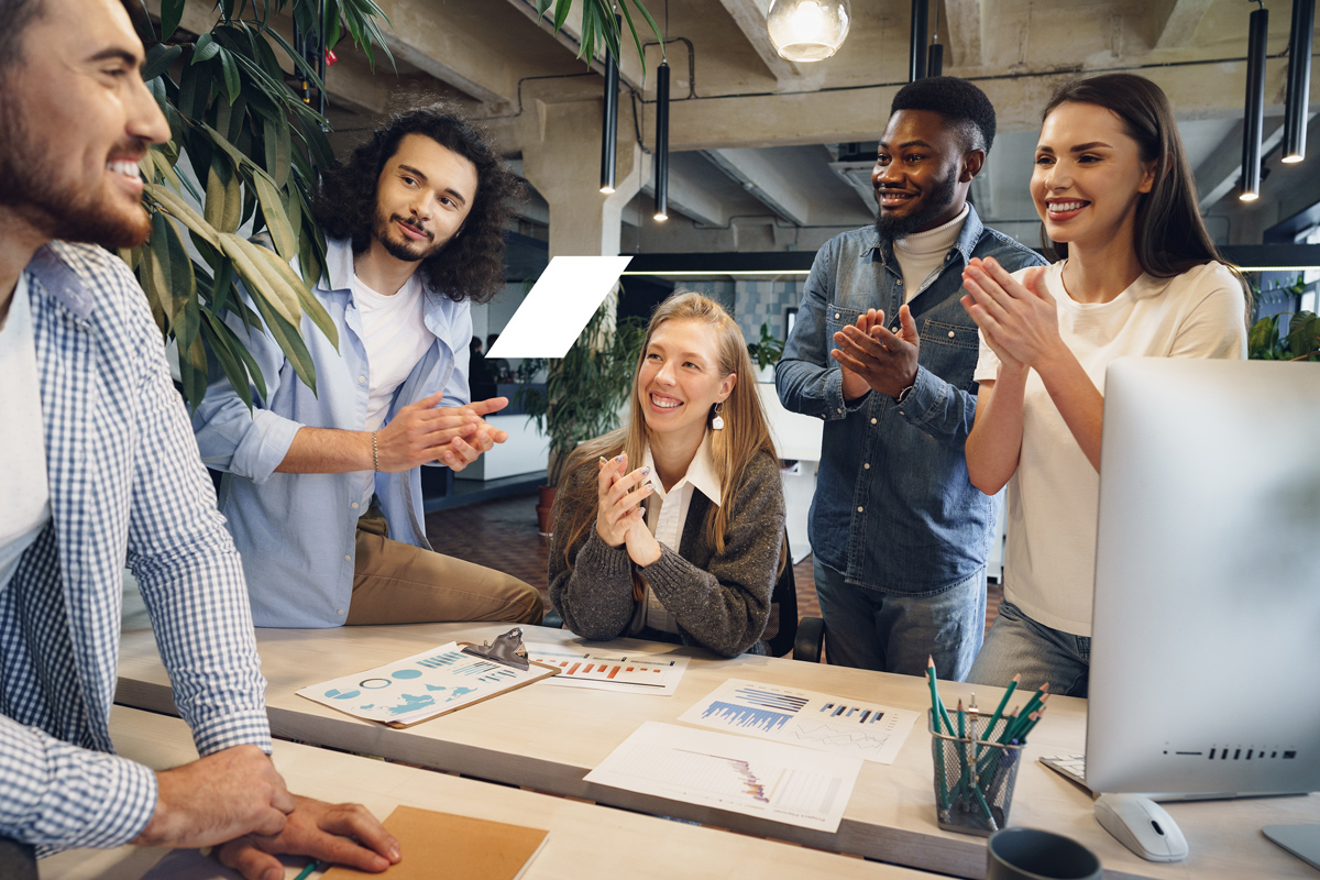 Grupo de jovens profissionais reunidos em um escritório moderno, conversando e celebrando resultados enquanto fortalecem o networking e a colaboração entre equipes.