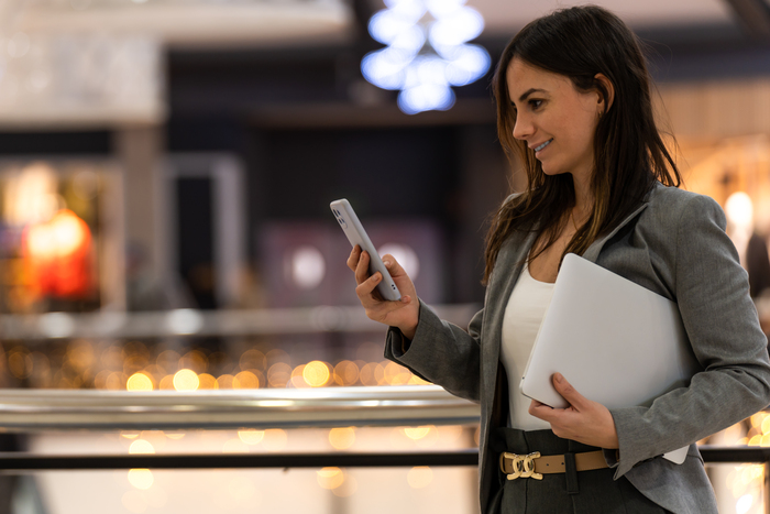 Profissional utilizando smartphone em ambiente corporativo moderno, representando estratégias de como localizar estrategicamente empresa com endereço fiscal em coworking e a importância da localização estratégica para negócios digitais e serviços.