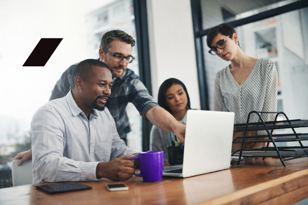 Profissionais trabalhando em estações individuais em um escritório moderno, representando o ambiente de trabalho presencial no contexto do trabalho híbrido e da cultura organizacional.