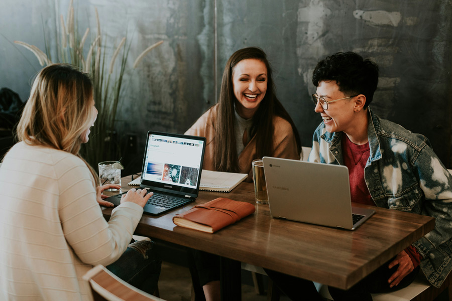 Pessoas trabalhando em mesas compartilhadas em coworking e se divertindo ao mesmo tempo