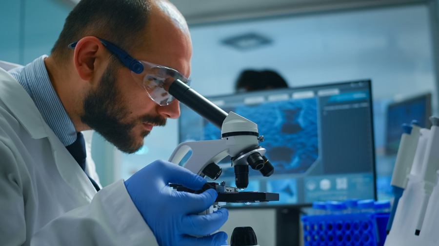 Profissional da área de biotecnologia realizando análise de material em microscópio, uma das atividades realizadas na região metropolitana de Ribeirão Preto.